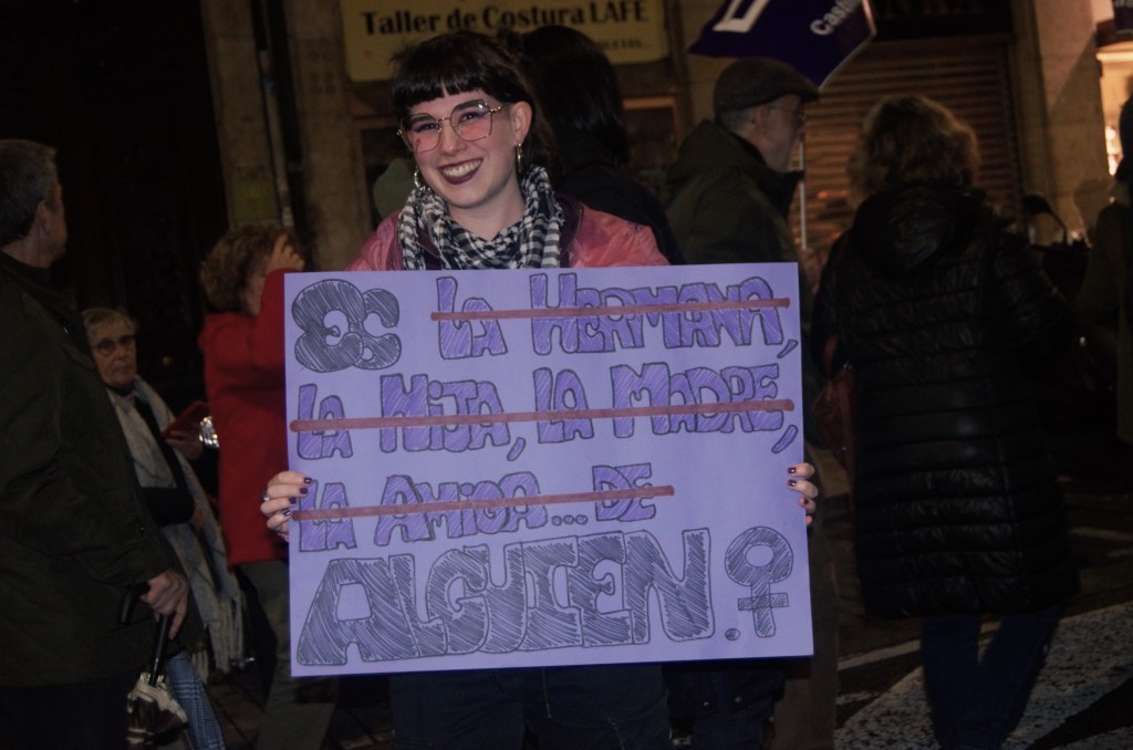 Joven sostiene un cartel en el que se lee: “Es (la hermana, la madre, la hija, la amiga…de) alguien”.